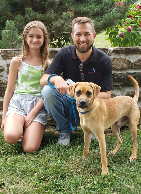 Man sitting next to daughter, with dog in the foreground. 