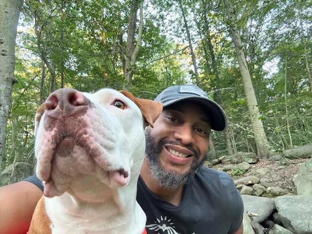 man in hat smiling next to dog